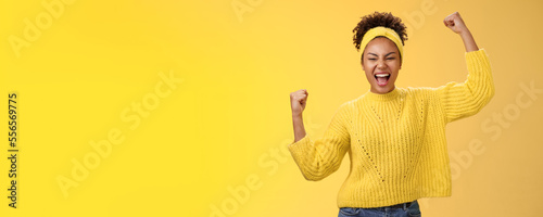 Active outgoing confident cheerful african-american female fan place bet hopefully yelling encourage team win standing raised fists victory celebrating gesture shouting proudly, yellow background photo