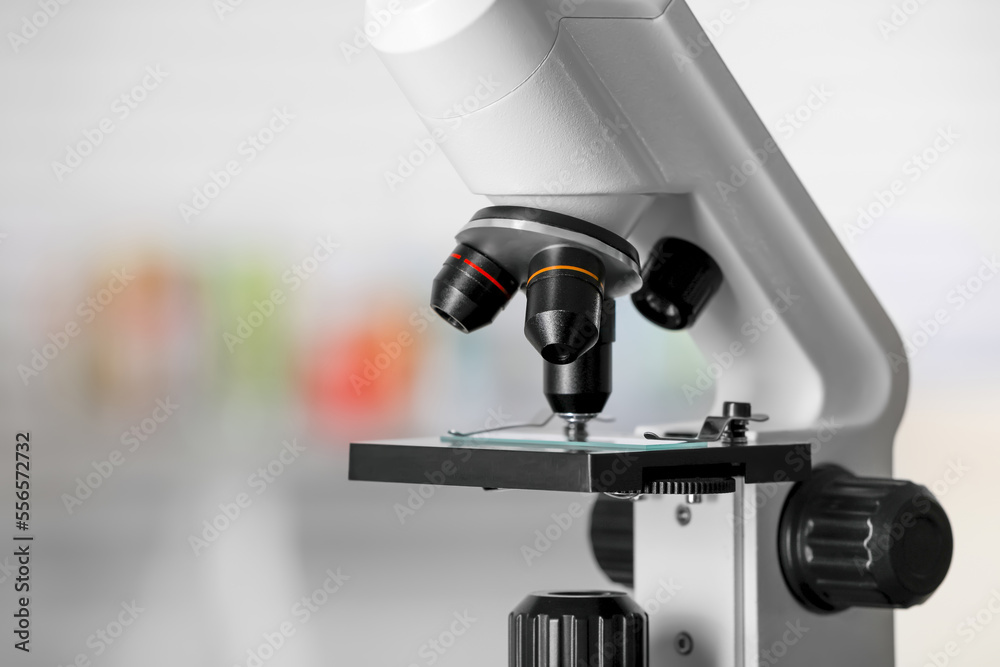 Modern medical microscope with glass slide on blurred background, closeup. Space for text
