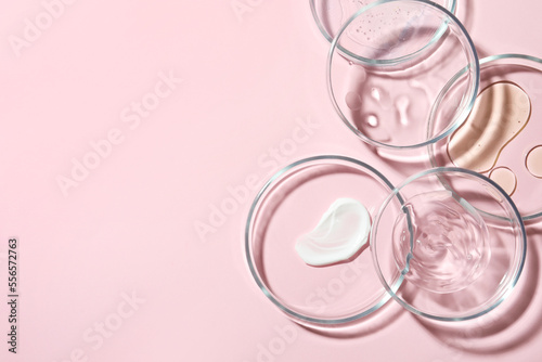 Many Petri dishes with cosmetic samples on pink background, flat lay. Space for text