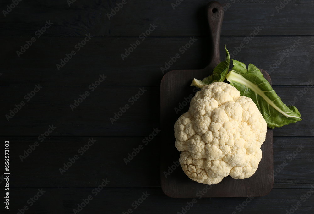 Fresh raw cauliflower on black wooden table, top view. Space for text