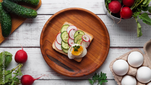 Tasty sandwich with boiled egg, radish, cucumber and ingredients on white wooden table, flat lay
