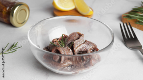Canned anchovy fillets in glass bowl on white marble table