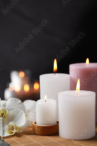 Burning candles and flowers against black background. Spa therapy