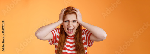 Pissed fed up redhead female teenager annoyed, break down, grab head yelling hateful displeased, depressed, upset failure, stand angry disappointed, panic, shouting aggressive orange background photo