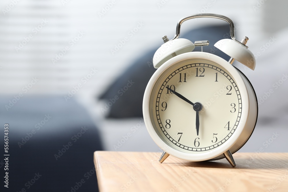 White alarm clock on wooden nightstand in bedroom, space for text White alarm clock on wooden nightstand in bedroom, space for text