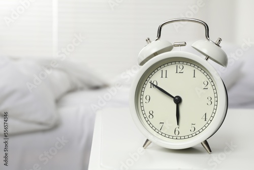Alarm clock on white nightstand in bedroom, space for text