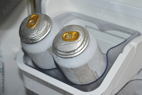 Two beer cans damaged and with bumps on the top because of too low temperature of the freezer.