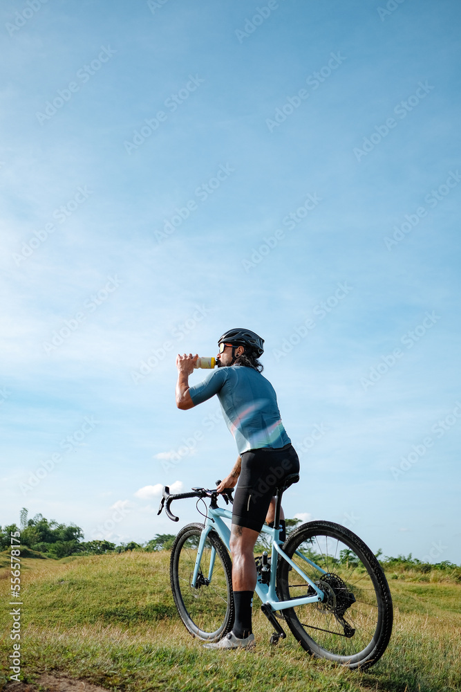 A young bearded cyclist is biking through a field A young bearded cyclist is biking through a field