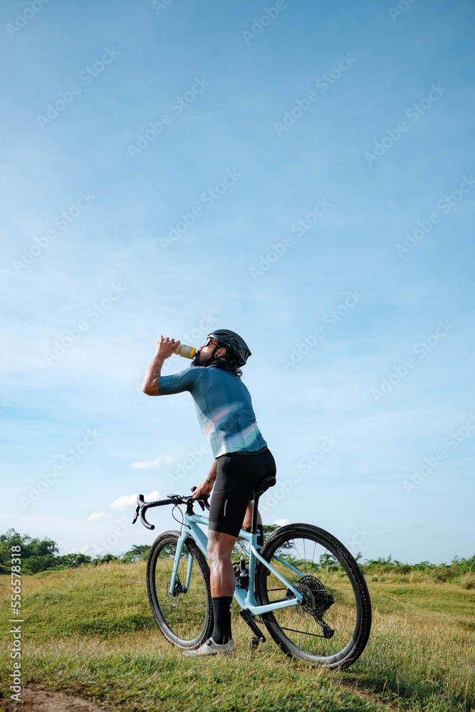 A young bearded cyclist is biking through a field A young bearded cyclist is biking through a field