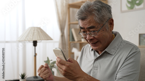 Emotional old asian man in glasses looking at cellphone screen celebrate winning mobile game or getting price in online lottery. elder male read message with unbelievable pleasant news on smartphone