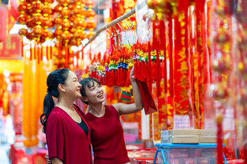 Asian woman mother and daughter holding shopping bag during buy home decorative ornament for celebrating Chinese Lunar New Year festival at Bangkok Chinatown street market. Chinese culture concept.