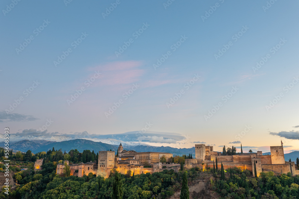 Aerial view of the Alhambra Palace in Granada, Spain with snow-capped Sierra Nevada mountains in the background.
