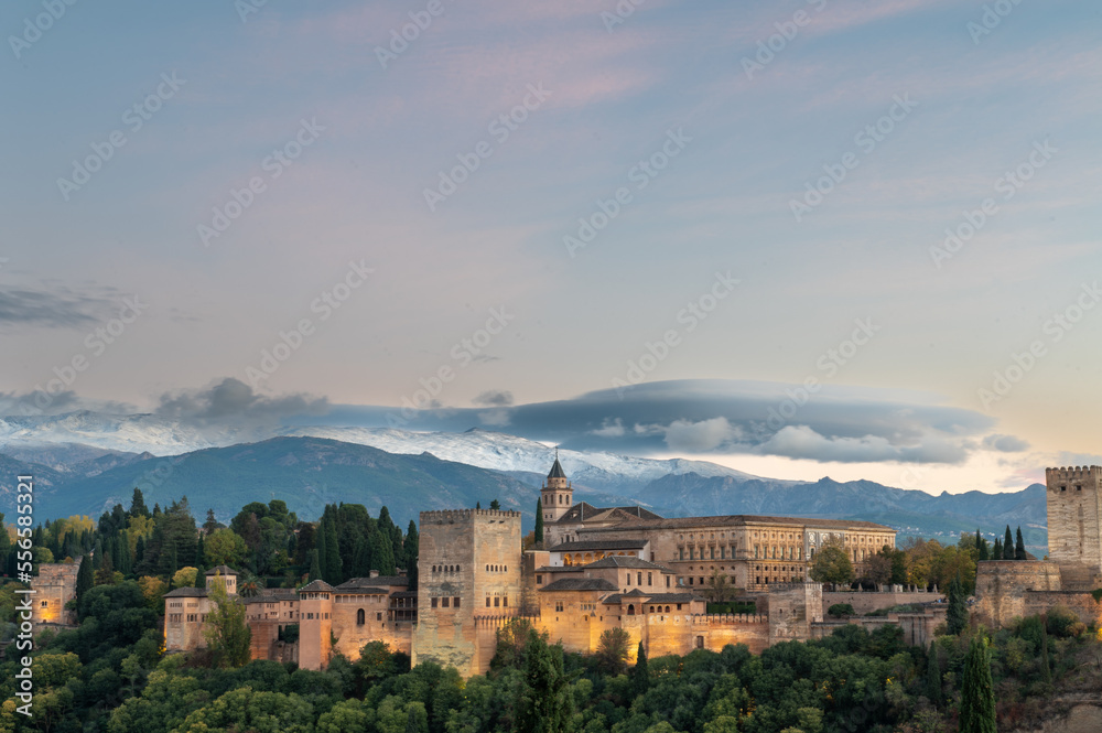Aerial view of the Alhambra Palace in Granada, Spain with snow-capped Sierra Nevada mountains in the background.