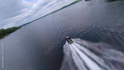 FPV drone video following two jetskis taking off from a dock on a lake in summer in Canada photo