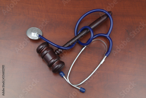 Judge gavel with stethoscope on wooden table, top view. Malpractice and crimes in medicine concept.