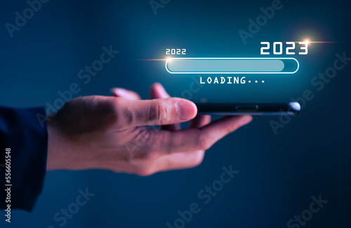 Businessman hand touching and pointing on loading bar year 2023 with virtual screen from 2022 to 2023, Businessman plan and increase of positive indicators in his business, Growing up business concept