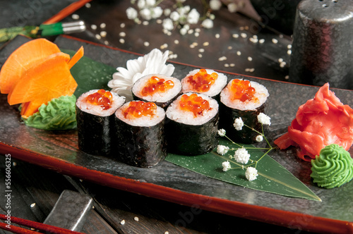 Sushi rolls with salmon and hot tea ceremony on black wooden table