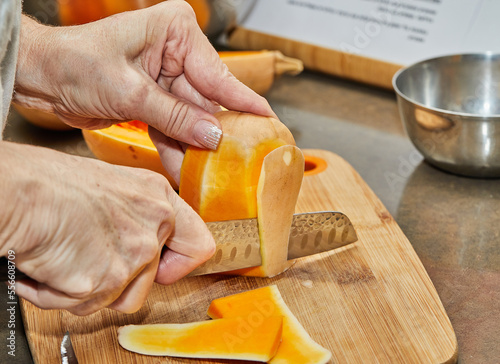 Chef cuts pumpkin in the shape of pear on wooden board in the home kitchen