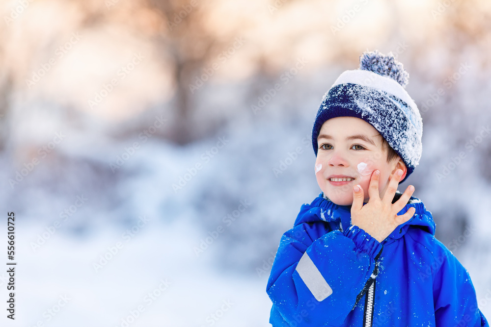 portrait of smiling little boy applying cold cream to face portrait of smiling little boy applying cold cream to face