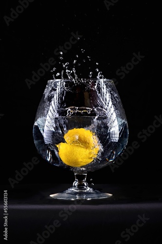 lemon splashing into water in wine glass on black background 