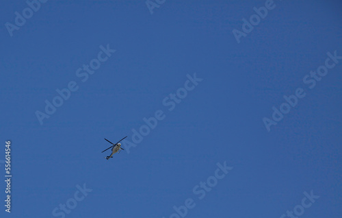 A police helicopter in flight against a blue cloudless sky.