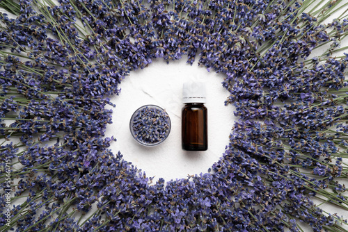 Lavender essential oil and dried flowers isolated over white concrete background. Top view, flat lay.