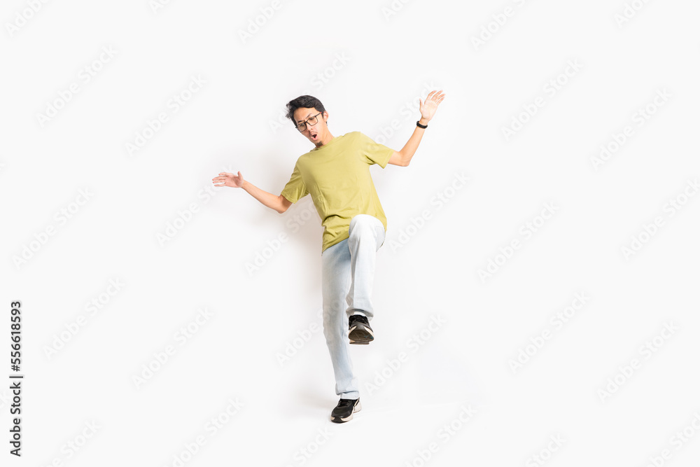 A single skinny young male tries to balance his body with one foot. The full body of an Asian or Indonesian person. Isolated photo studio with white background.