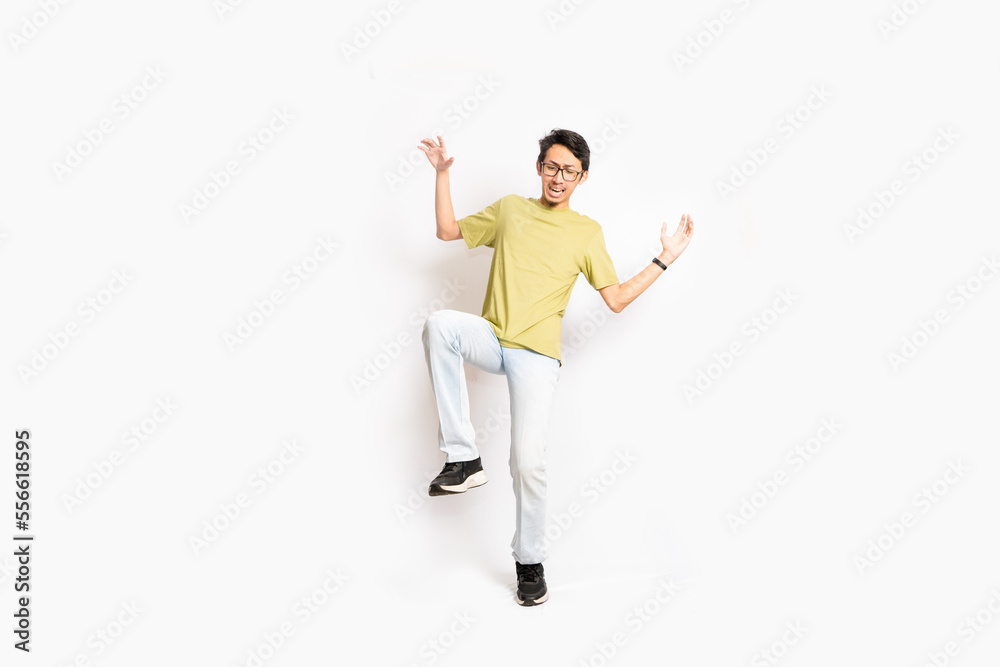A single skinny young male tries to balance his body with one foot. The full body of an Asian or Indonesian person. Isolated photo studio with white background.