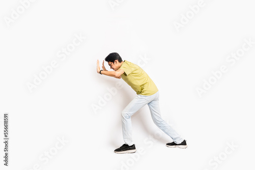 The single skinny young male tries to push something sideways. The full body of an Asian or Indonesian person. Isolated photo studio with white background.