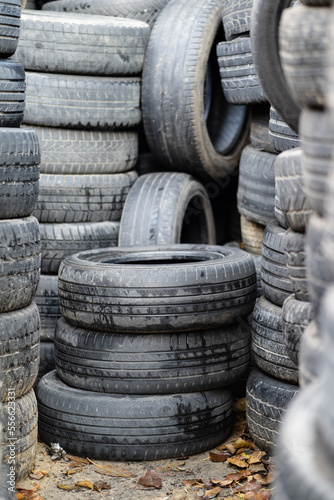 Old used rubber tires stacked with high piles. Tyre dump. Hazardous waste requiring recycling and disposal. 