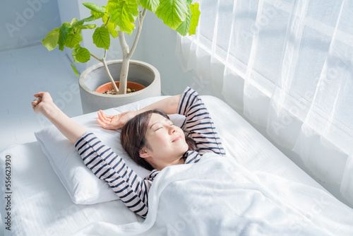 ベッドからの目覚めがよく伸びをする女性