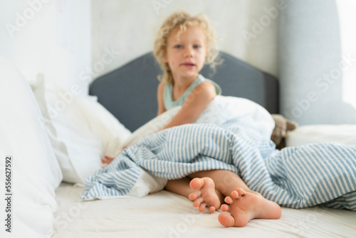 Girl with duvet sitting on bed at home photo