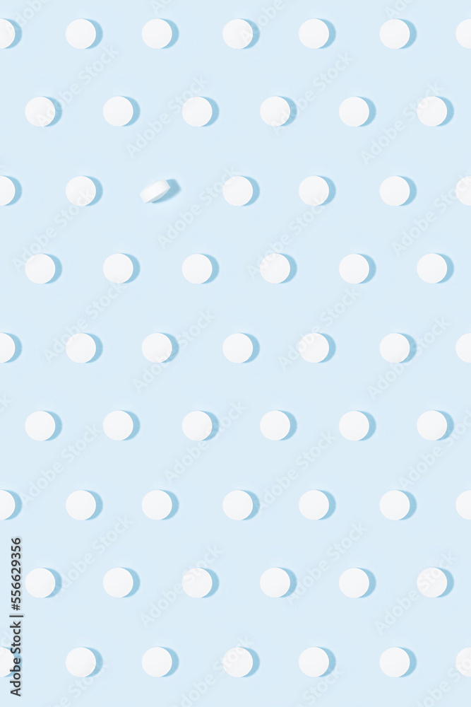 Health and pharmacy remedies for prevent and teraphy disease and illness background - white pills seamless pattern on pastel blue color in hard light with shadow, top view, vertical. Health and pharmacy remedies for prevent and teraphy disease and illness background - white pills seamless pattern on pastel blue color in hard light with shadow, top view, vertical.
