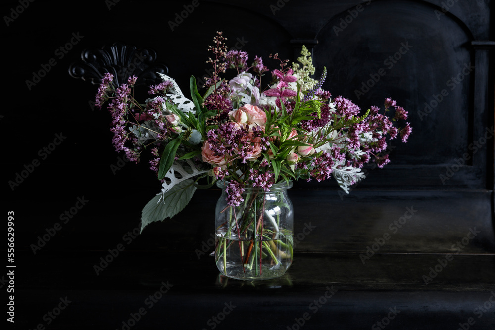 Bunch of flowers in glass jar on black piano Bunch of flowers in glass jar on black piano