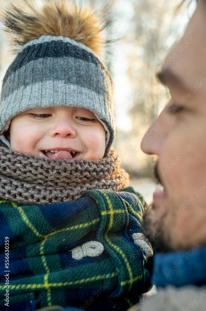 Man looking at son sticking out tongue in winter