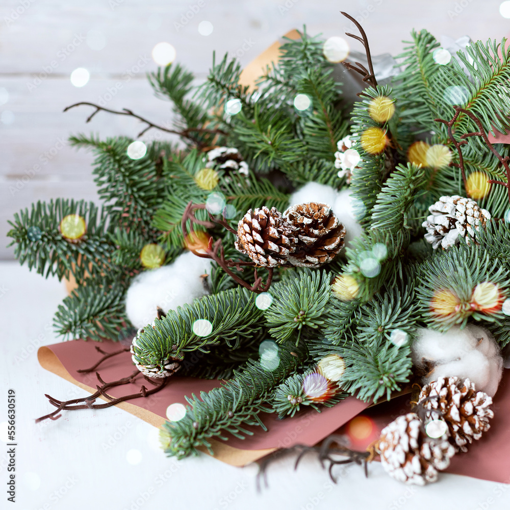 Beautiful winter bouquet of fresh Nobilis spruce, pine cones and cotton. Winter decor hand-made, work florist. Selective focus. Close up. Square Beautiful winter bouquet of fresh Nobilis spruce, pine cones and cotton. Winter decor hand-made, work florist. Selective focus. Close up. Square