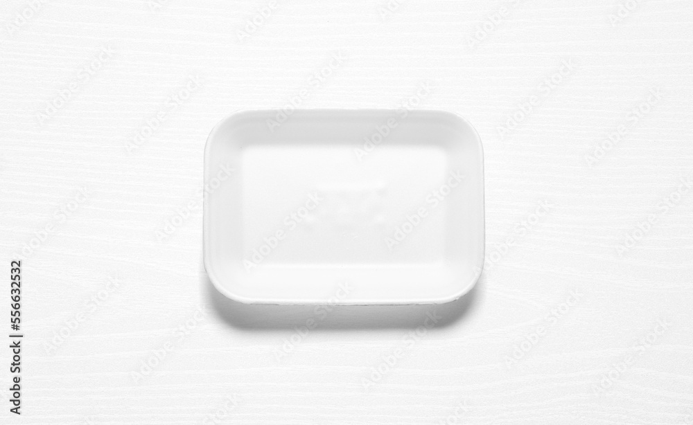 White styrofoam tray against a white wood board White styrofoam tray against a white wood board