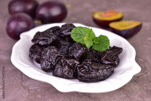 Dried plums or prunes in a plate on a gray background.Close-up.
