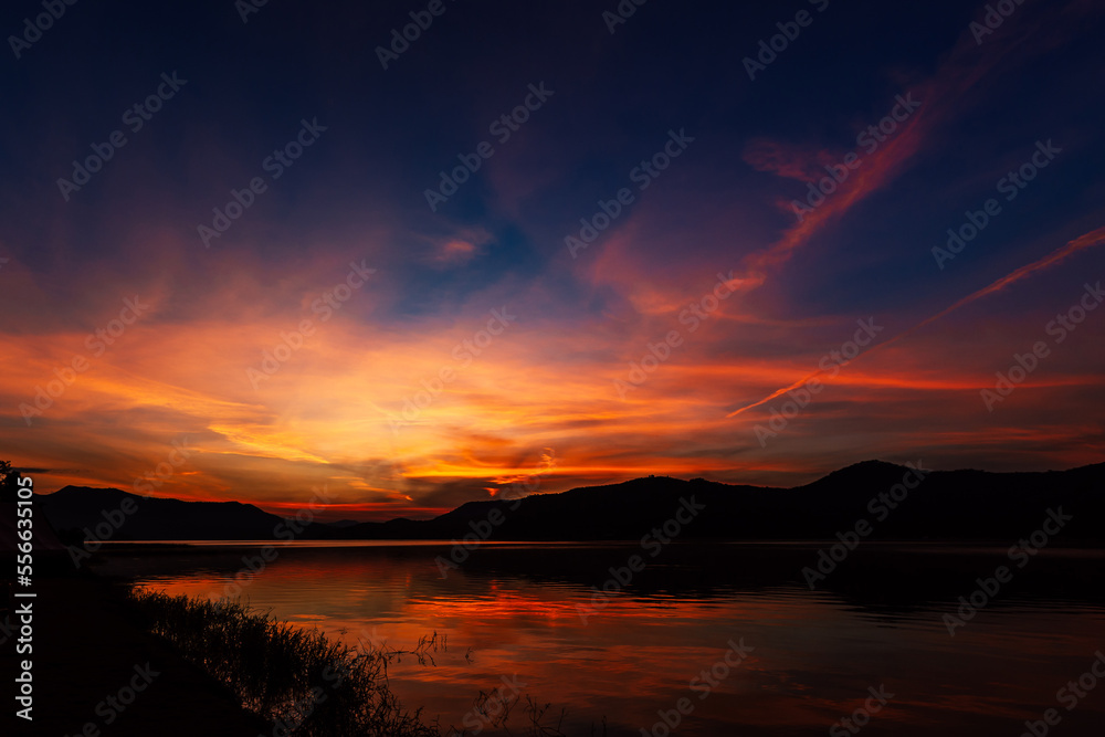 Sunrise time at lake or river with mountain on the background. in dark tone.