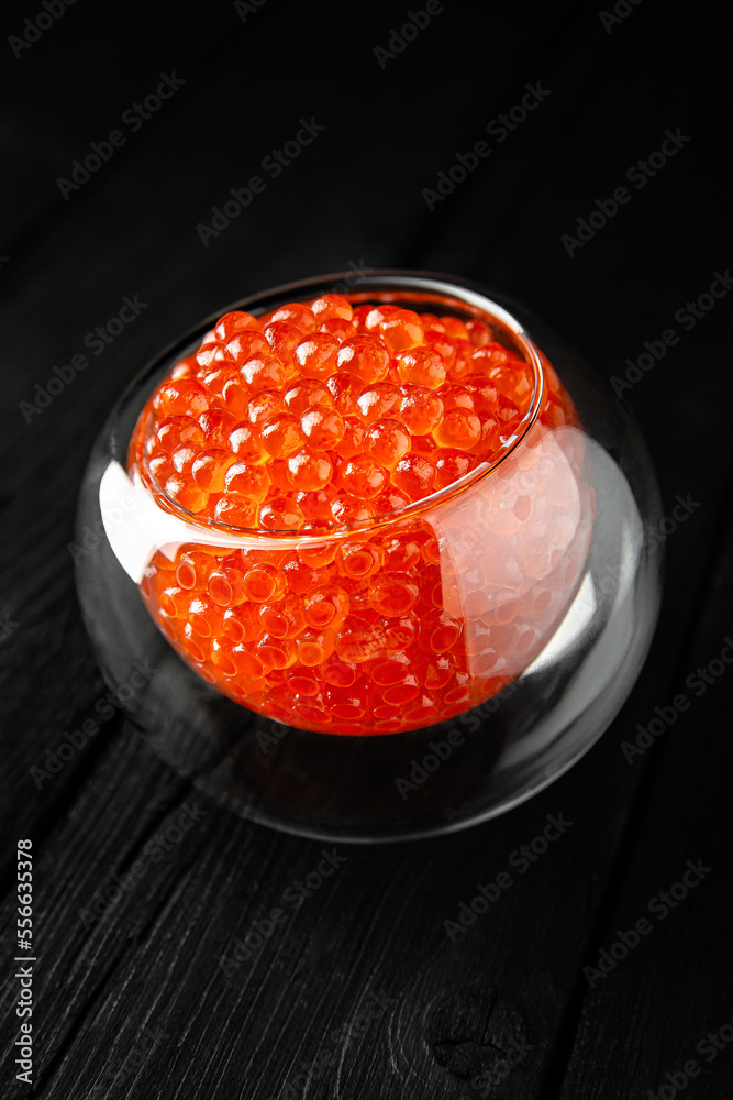 Red caviar in a crystal bowl on a black background. Delicacy product of the highest quality. Red caviar in a crystal bowl on a black background. Delicacy product of the highest quality.