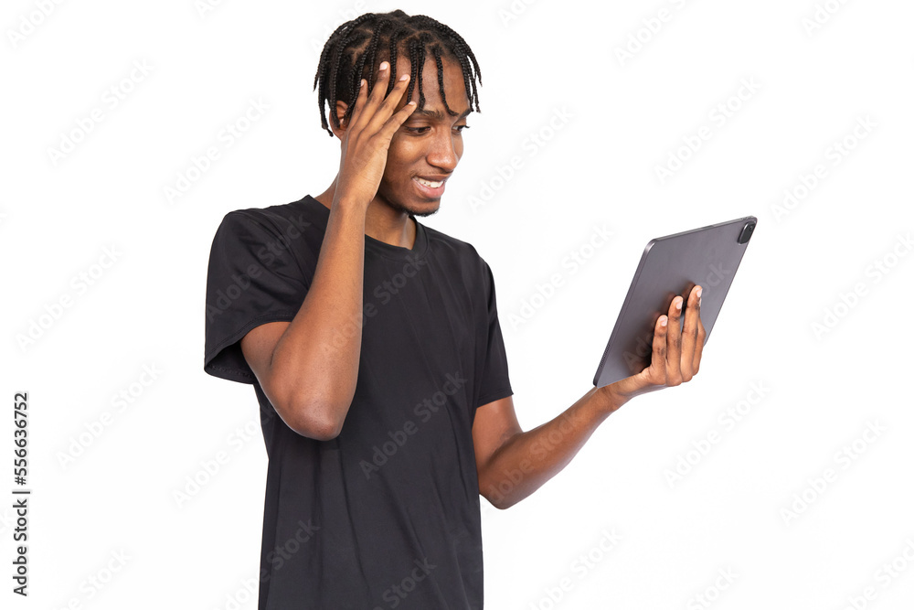 Surprised young man reading news on digital tablet. Male African American model with brown eyes and afro braids in casual clothes opening mouth from surprise reading message. Modern technology concept Surprised young man reading news on digital tablet. Male African American model with brown eyes and afro braids in casual clothes opening mouth from surprise reading message. Modern technology concept