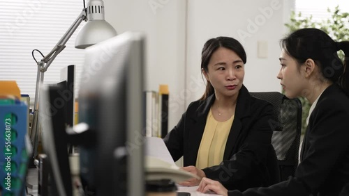 slow motion with selective focus asian young woman intern looking at computer and document while learning new skills with her mentor coach in the office