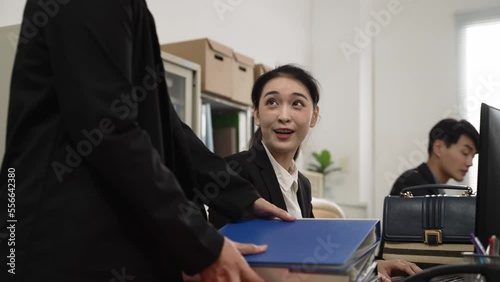 asian female worker refusing doing more work for her manager and leaving the office with her bag. frustrated team leader looking at stack of documents with a sigh