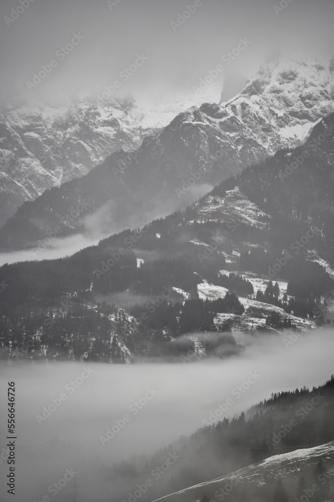 Obraz premium Dreamy mysterious winter landscape with fog and snow covered mountains and trees