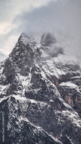 Dreamy mysterious winter landscape with fog and snow covered mountains and clouds in the sky