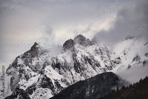 Dreamy mysterious winter landscape with fog and snow covered mountains and clouds in the sky