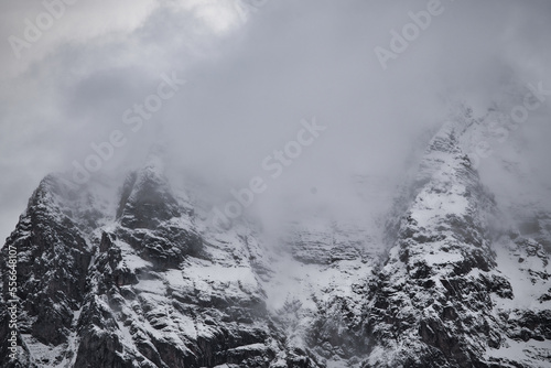 Dreamy mysterious winter landscape with fog and snow covered mountains and clouds in the sky © Hanjin