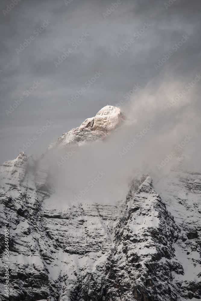 Dreamlike mysterious winter landscape with fog and snow covered mountains and clouds in the sky