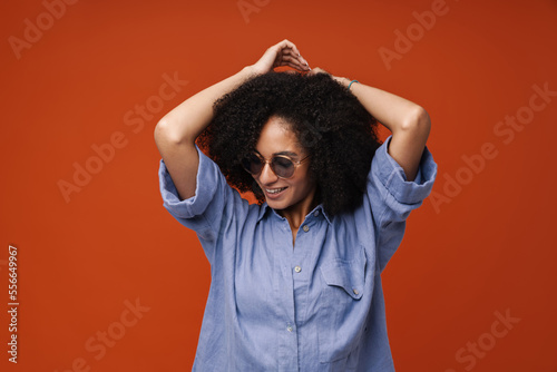 Young woman with curly hair in sunglasses smiling at camera
