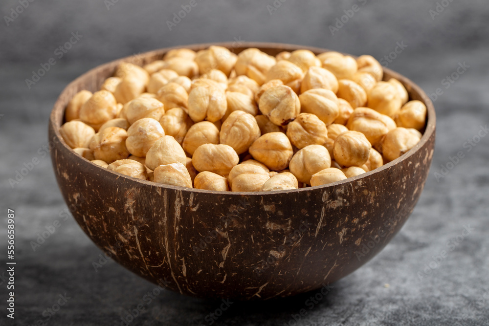 Roasted hazelnuts in bowl on dark background. Nuts in a coconut bowl. close up Roasted hazelnuts in bowl on dark background. Nuts in a coconut bowl. close up